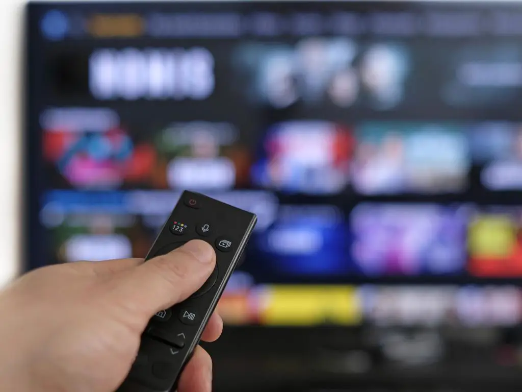 Gambar remote TV dan layar TV menampilkan berita